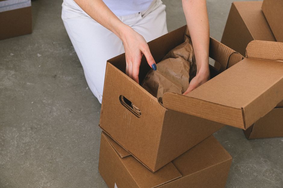 Movers packing cardboard boxes in a living room