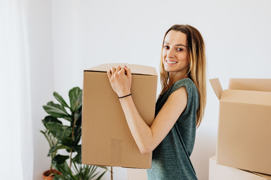 Movers carrying moving boxes carefully out of a residential home